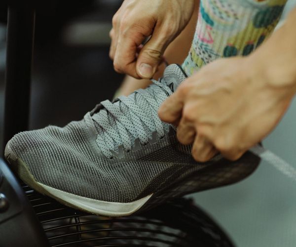 Detail of a person tying sneakers in a dark gym